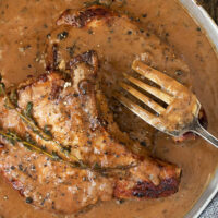 pork chops with peppercorn sauce in pan with fork