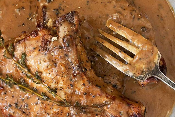 pork chops with peppercorn sauce in pan with fork