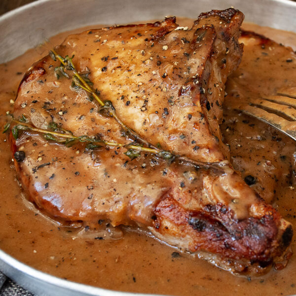 pork chops in peppercorn sauce in dish with fork