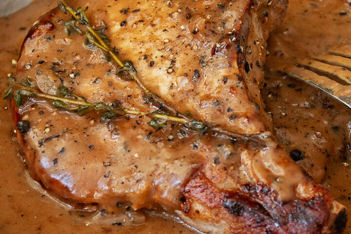 pork chops in peppercorn sauce in dish with fork