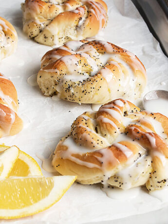 lemon poppy seed knots on baking sheet with lemon wedges