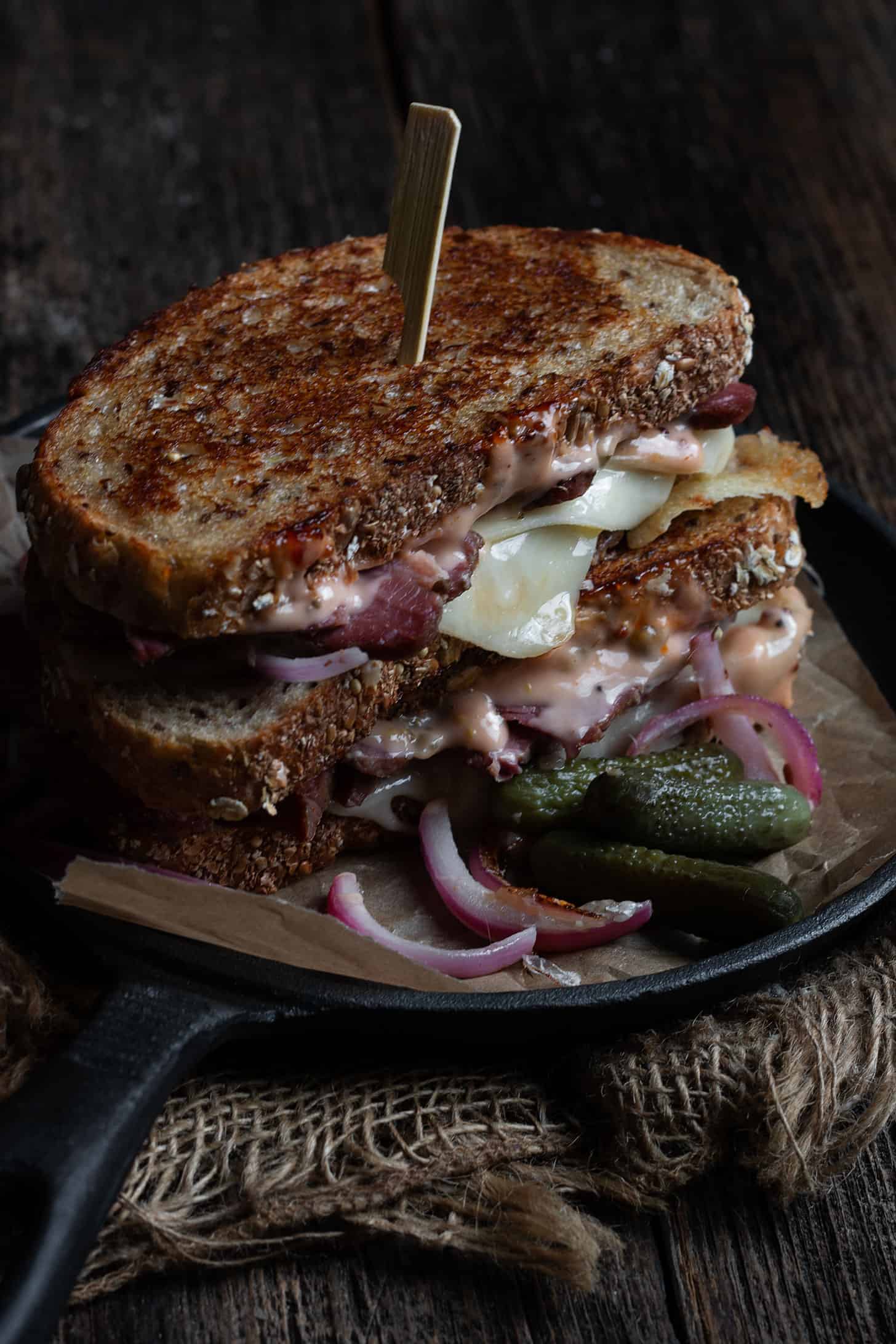 grilled reuben sandwich on platter with pickles