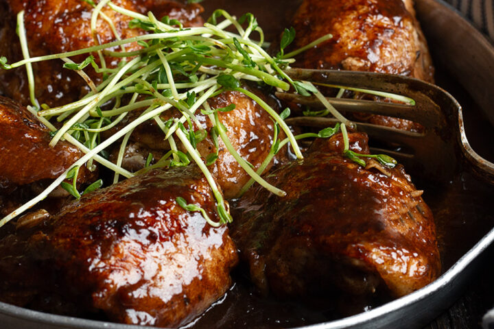 Balsamic chicken thighs on a serving plate.