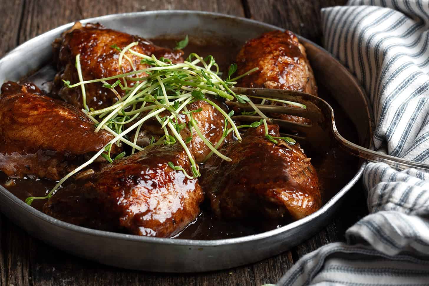 Balsamic chicken thighs on a serving plate.
