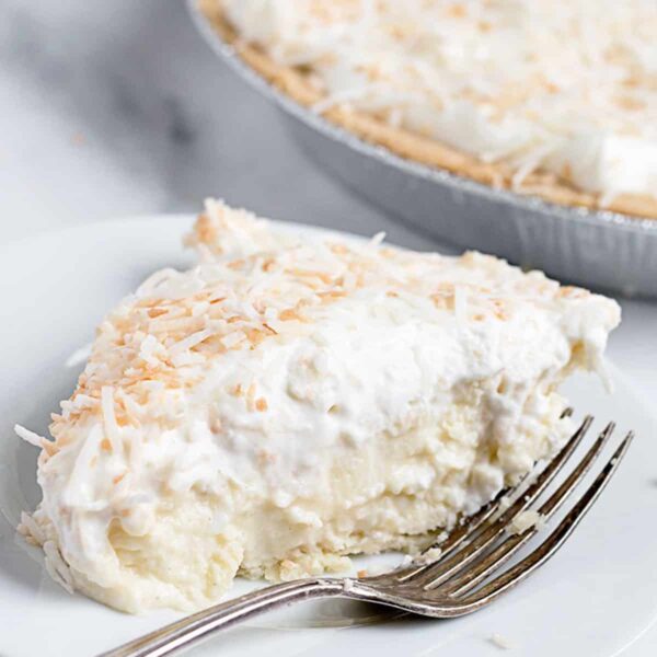 coconut cream pie slice on plate with pie behind