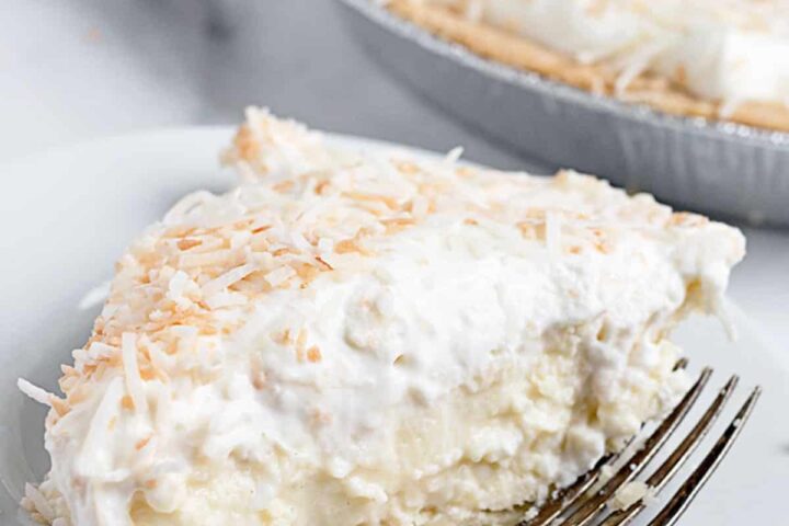 coconut cream pie slice on plate with pie behind