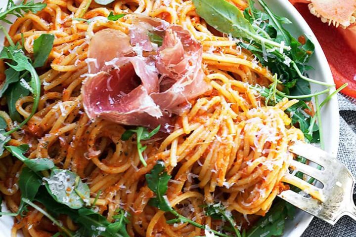 red pepper pasta on plate with prosciutto