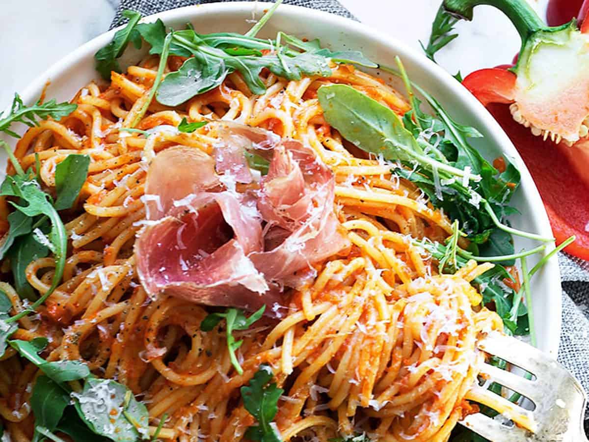 red pepper pasta on plate with prosciutto