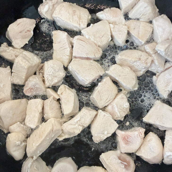 Coking chicken pieces in a skillet.