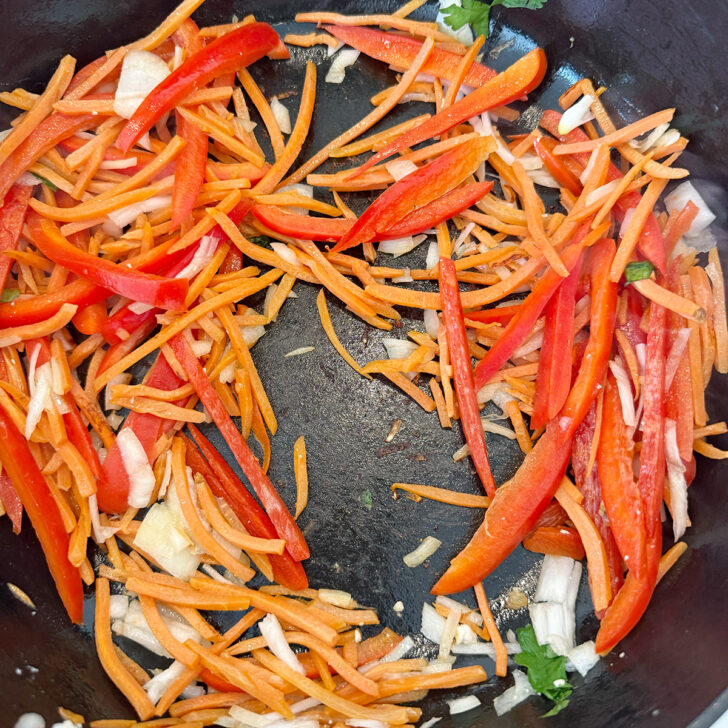 Cooking the carrot, onion and bell pepper in a skillet.