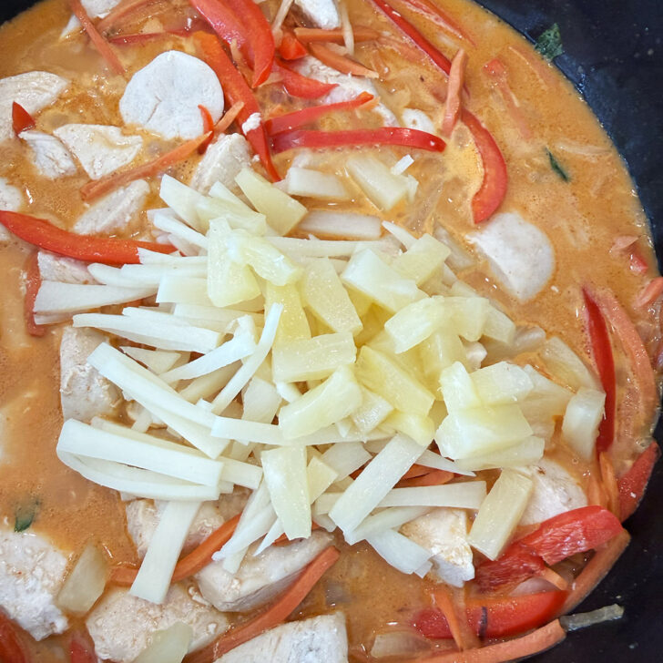 Adding bamboo shoots and pineapple to the skillet.