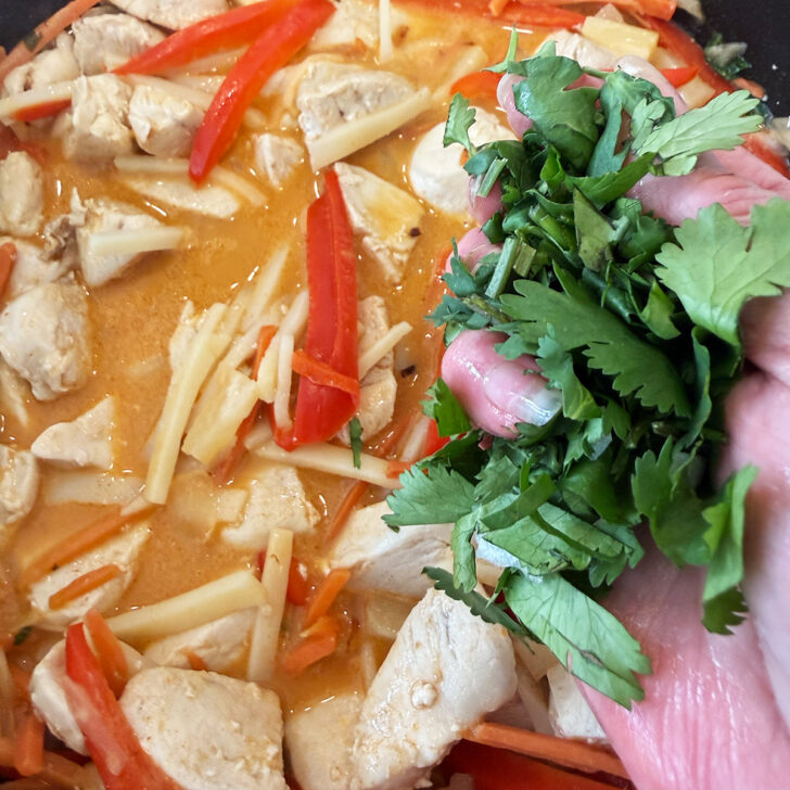 Adding chopped cilantro to the Thai red curry chicken.