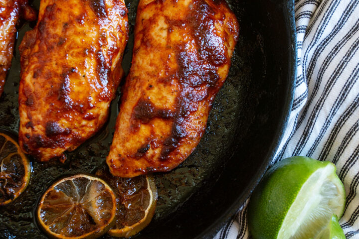 chili lime chicken in skillet with limes