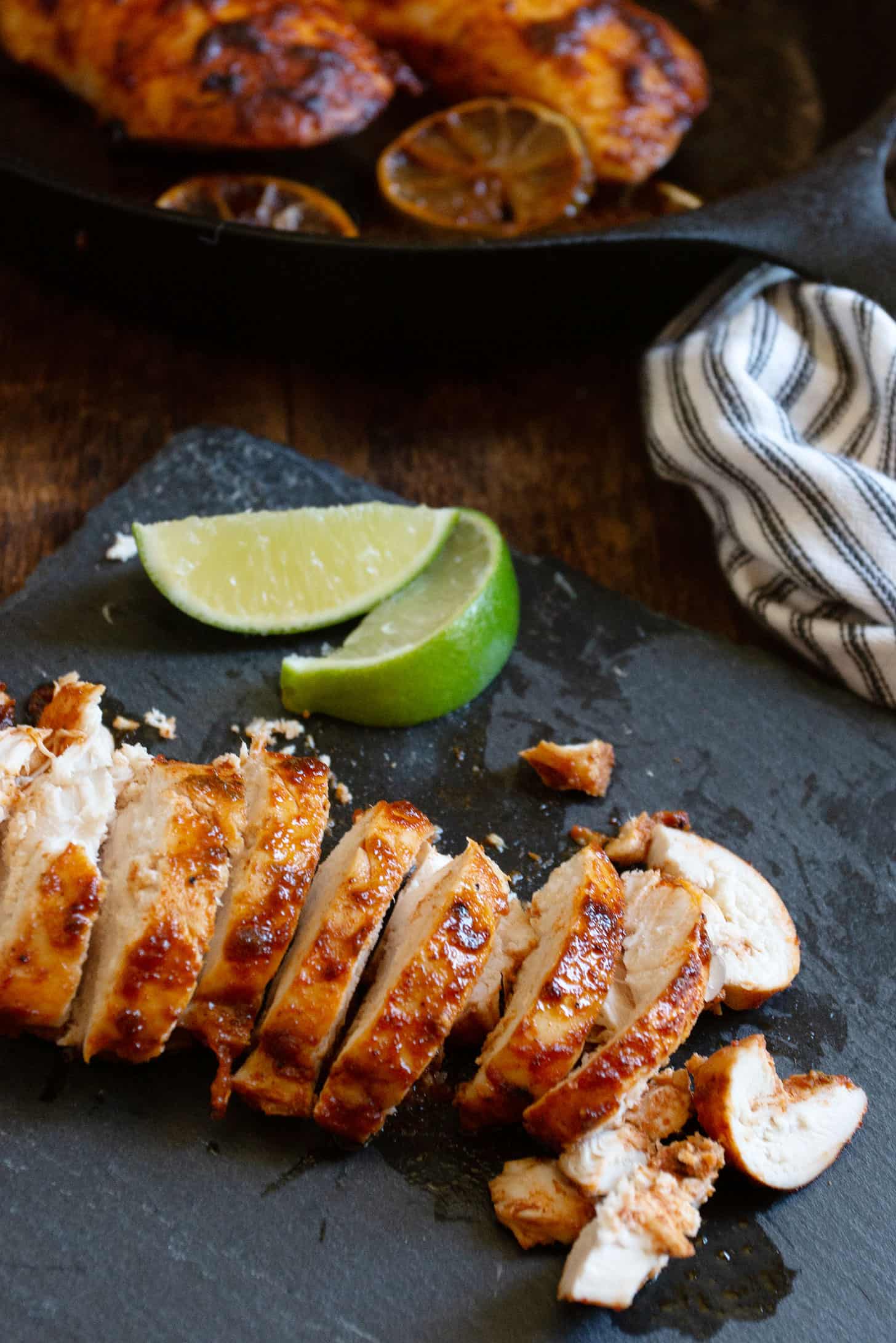 chili lime chicken in skillet with limes