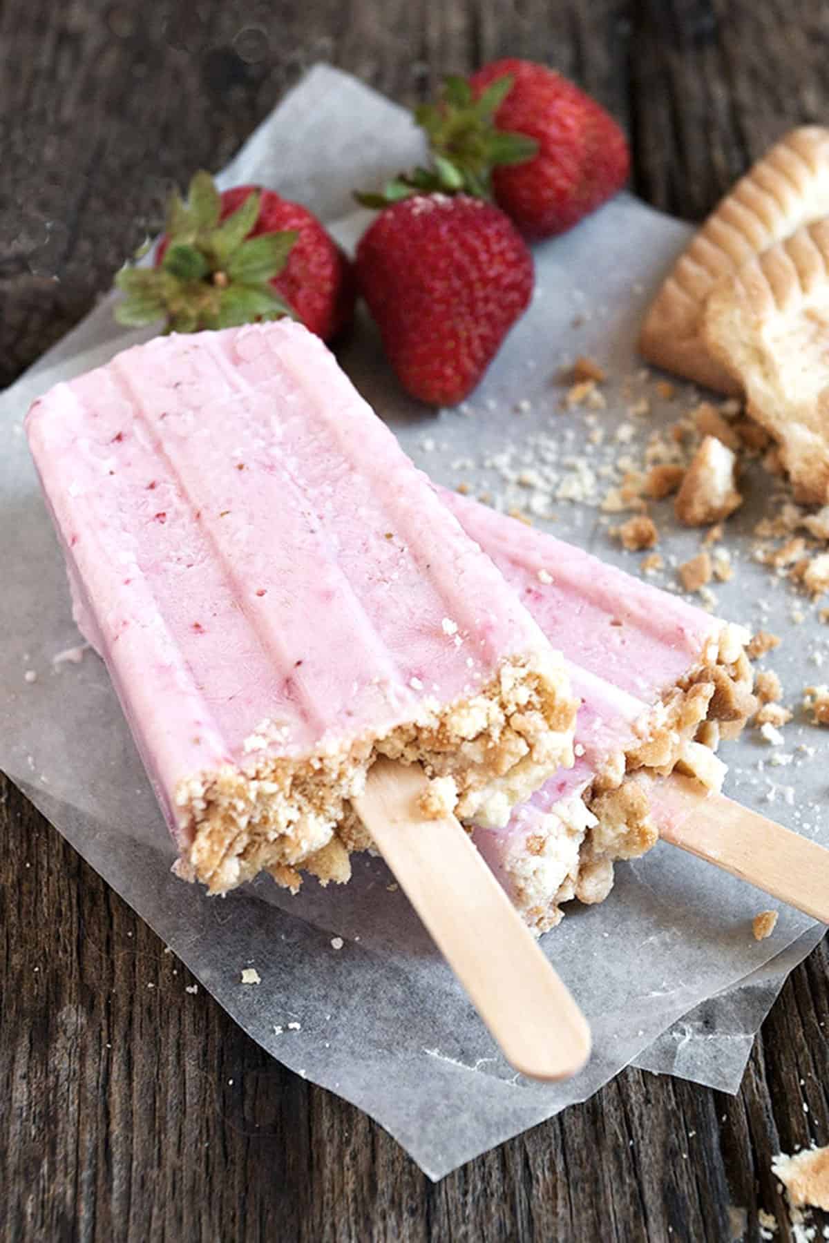 strawberry yogurt pops on parchment with strawberries