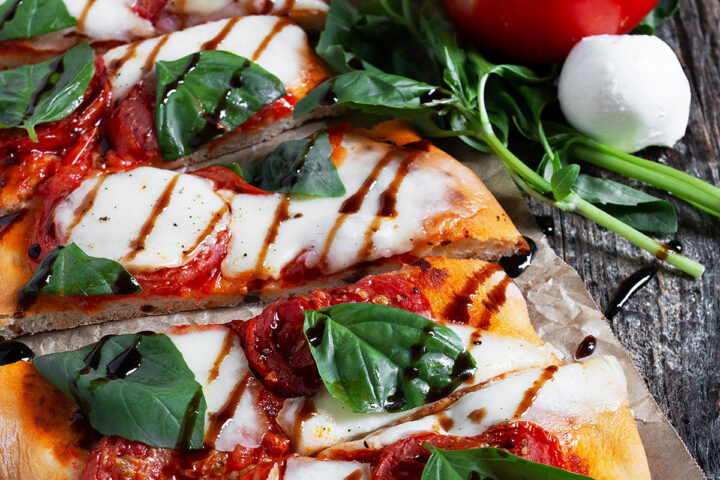 Tomato bocconcini flatbread sliced on parchment paper.