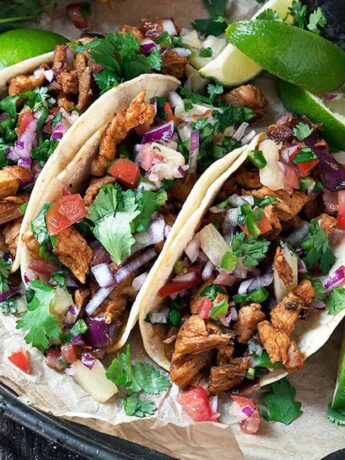 tacos al pastor on platter with lime slices