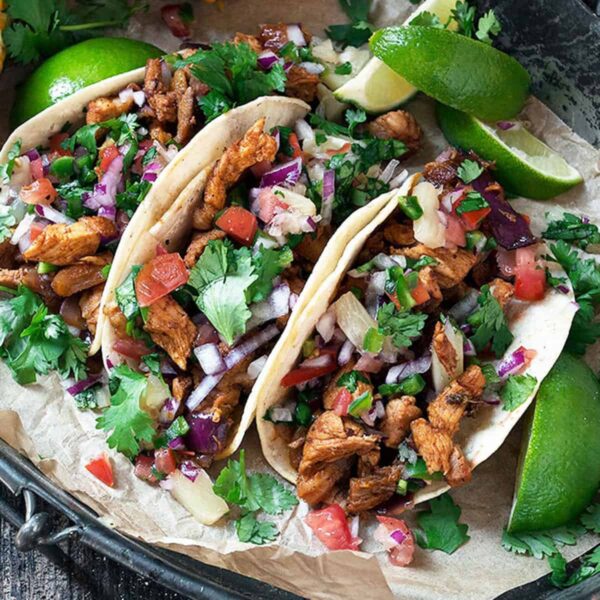 tacos al pastor on platter with lime slices