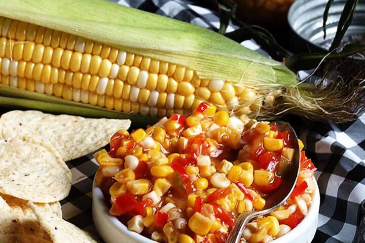 corn chile salsa in white bowl with corn cob