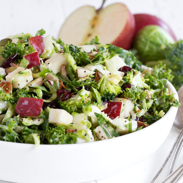 Fall kale and apple salad with Brussels sprouts and broccoli in a serving bowl.
