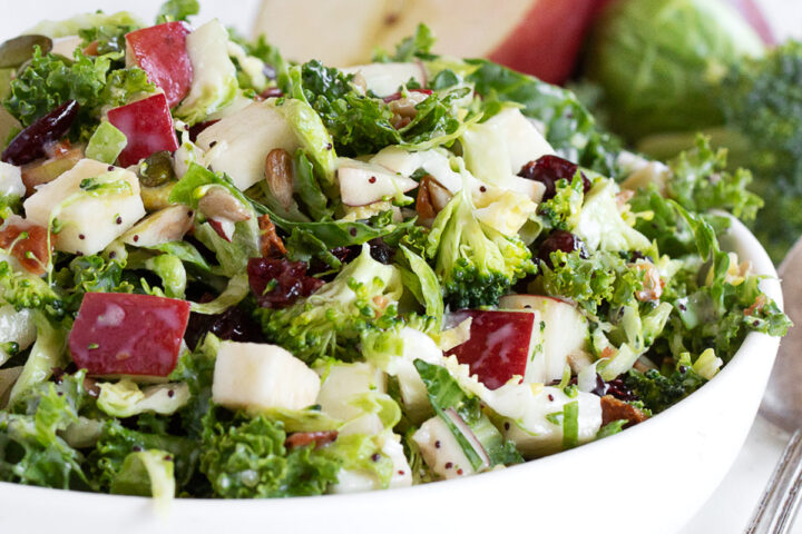Fall kale and apple salad with Brussels sprouts and broccoli in a serving bowl.