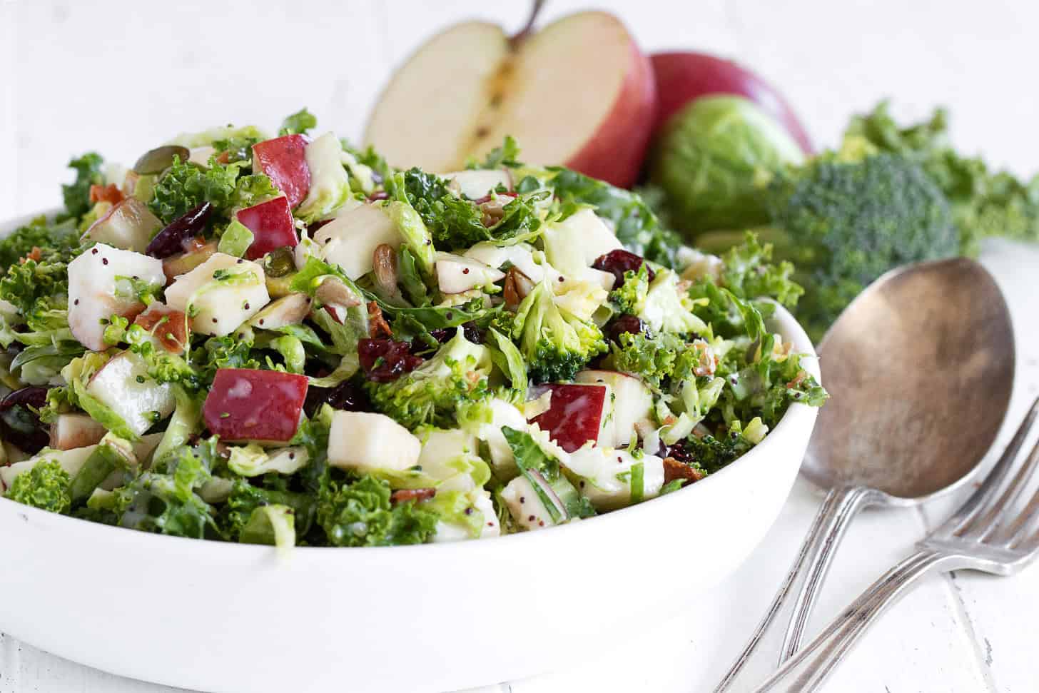 Fall kale and apple salad with Brussels sprouts and broccoli in a serving bowl.