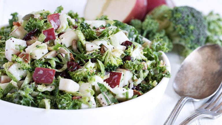 kale salad with apple in a white bowl