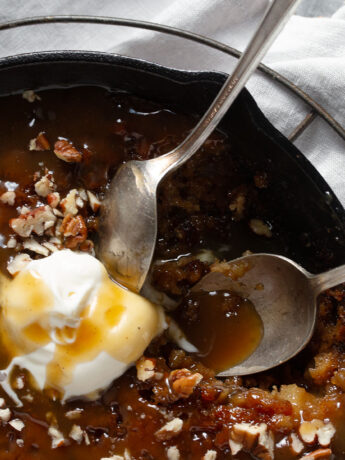 Apple sticky toffee pudding in a cast iron skillet with ice cream.