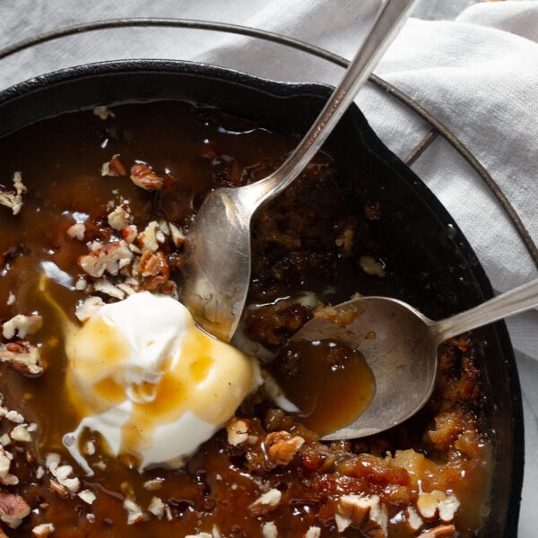 Apple sticky toffee pudding in a cast iron skillet with ice cream.