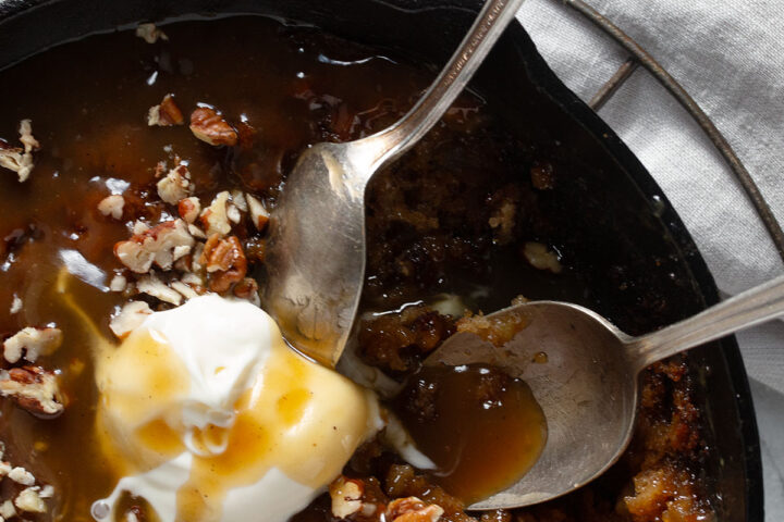 Apple sticky toffee pudding in a cast iron skillet with ice cream.