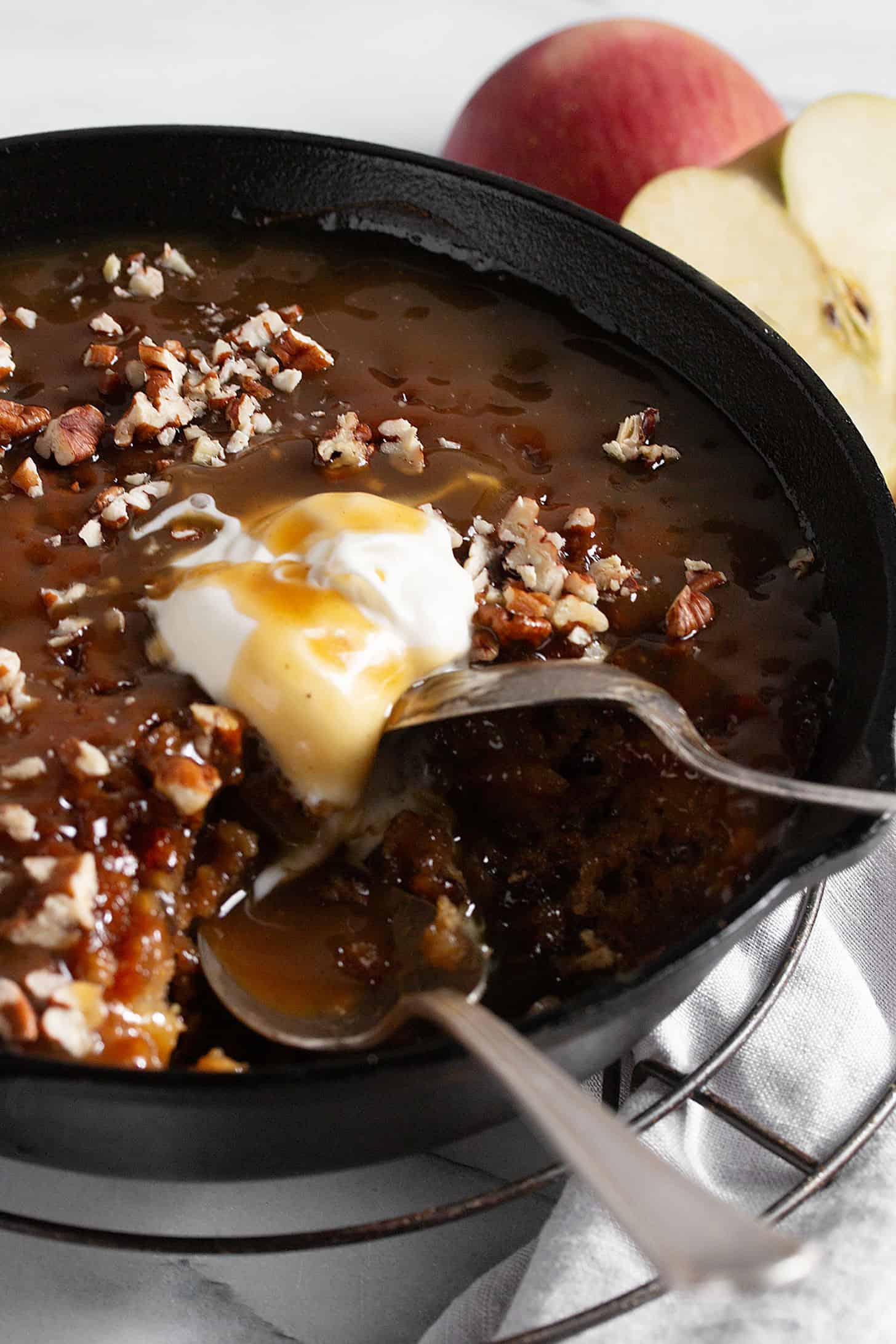 Apple sticky toffee pudding in a cast iron skillet with ice cream.