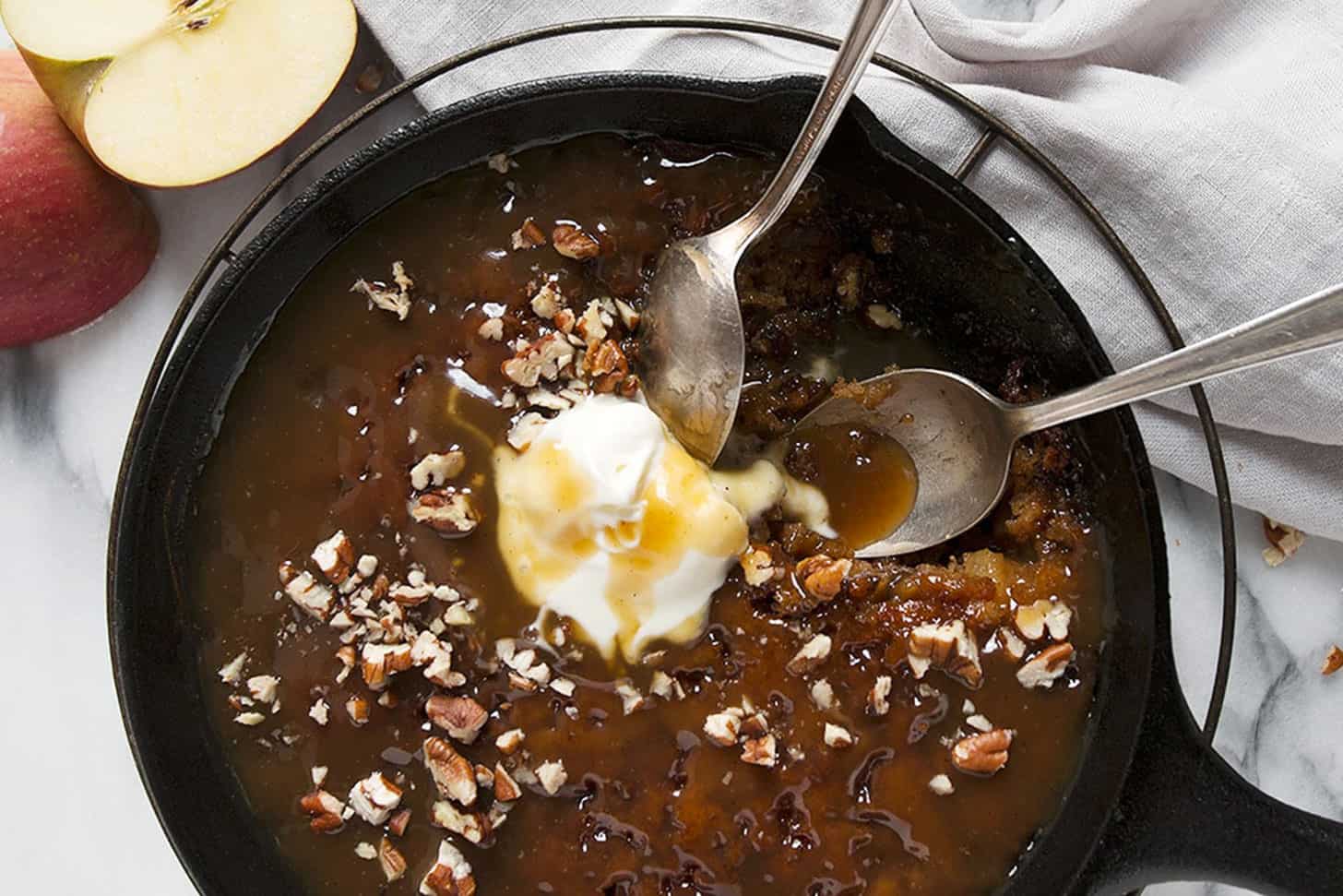 Apple sticky toffee pudding in a cast iron skillet with ice cream.