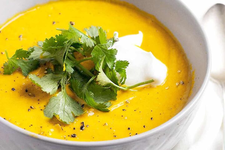 Thai carrot soup in bowls with cilantro and sour cream