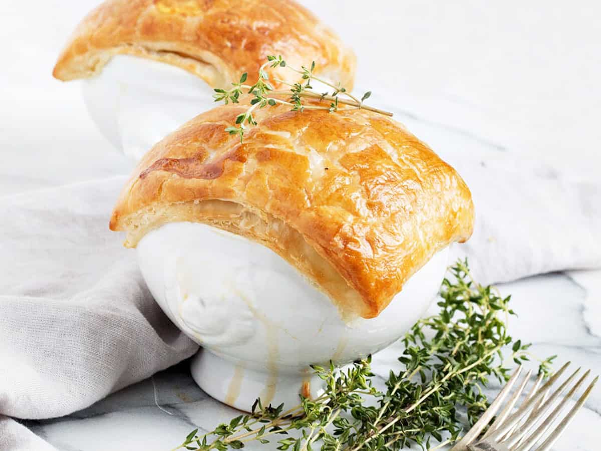 chicken pot pie in white bowls with puff pastry topping