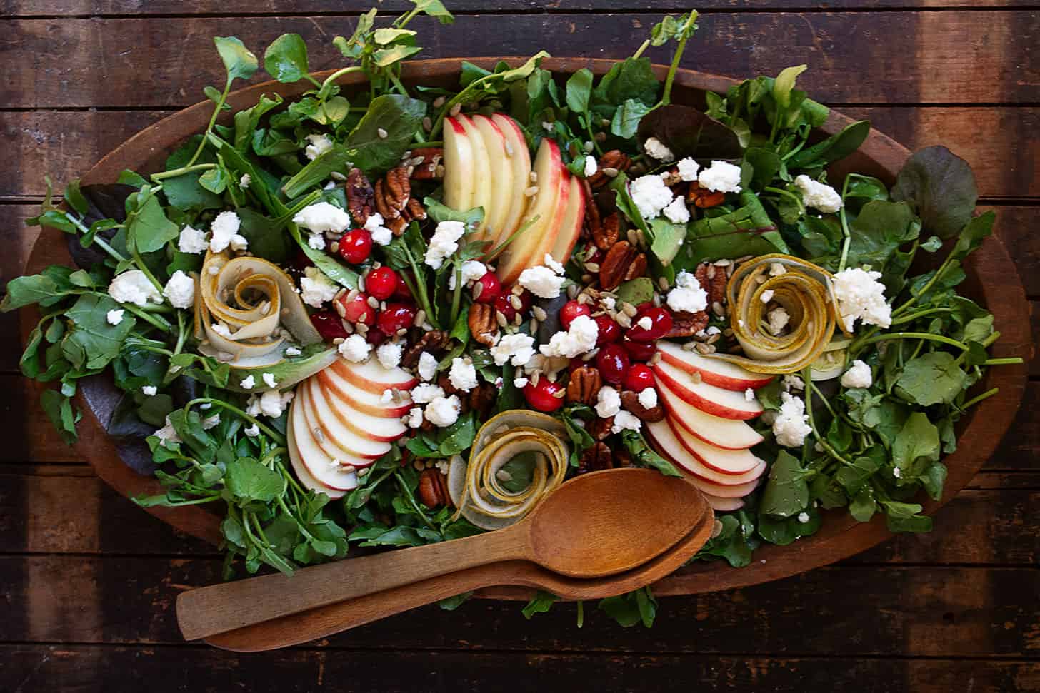 Fall harvest salad in wooden bowl with wooden spoons