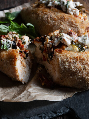 Goat cheese stuffed chicken on cutting board.