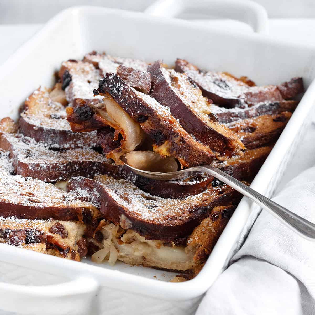 Gruyere and pear bread pudding in baking dish with spoon.