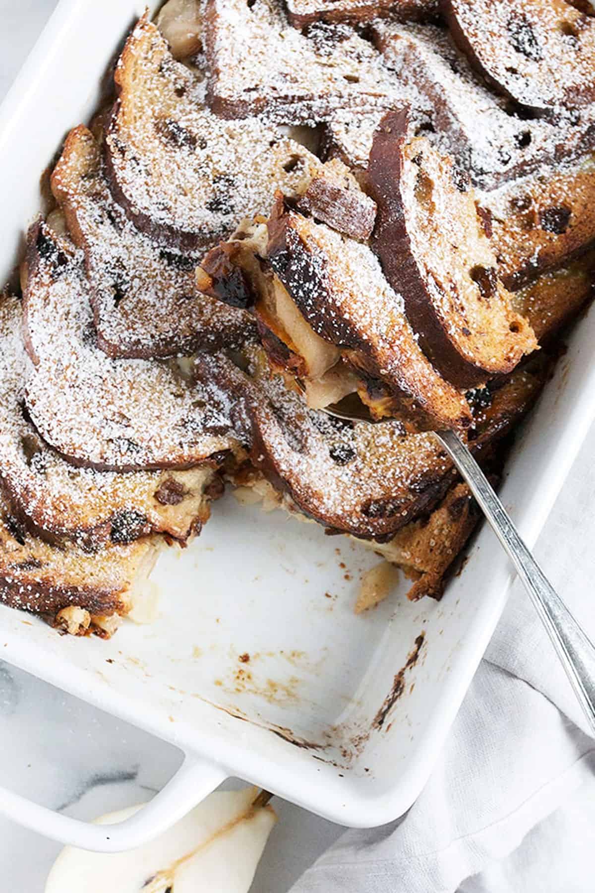 pear gruyere french toast in white baking dish with spoon