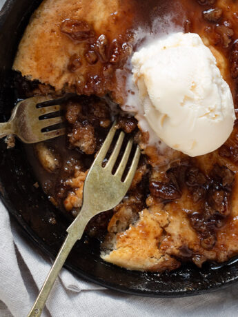 pecan pie cobbler in small cast iron skillet with ice cream