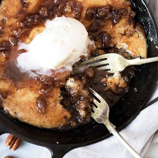 pecan pie pudding cake in cast iron skillet with forks
