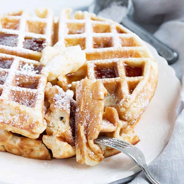 waffles on plate with butter, cut with fork