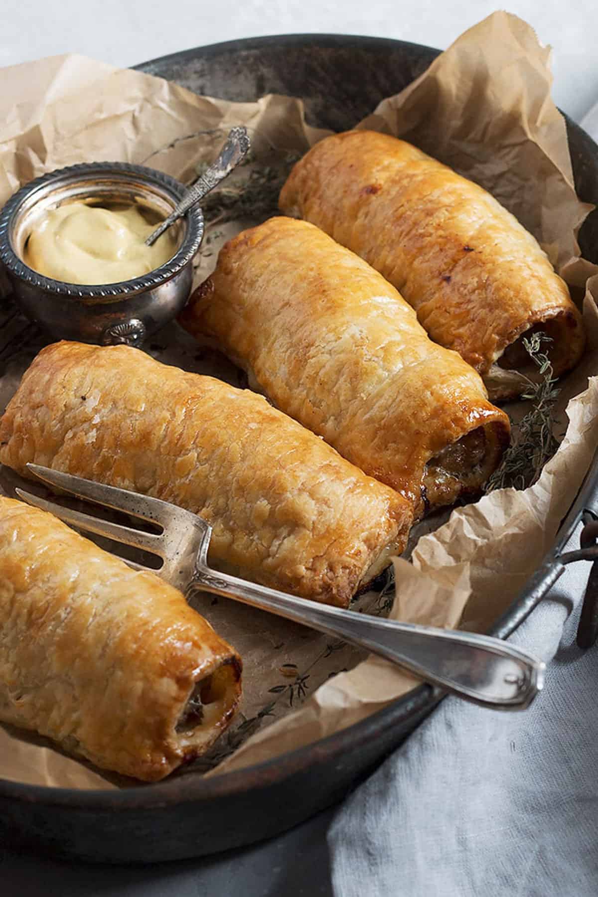 homemade sausage rolls on platter with mustard