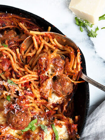 baked spaghetti and meatballs in cast iron skillet with spoon