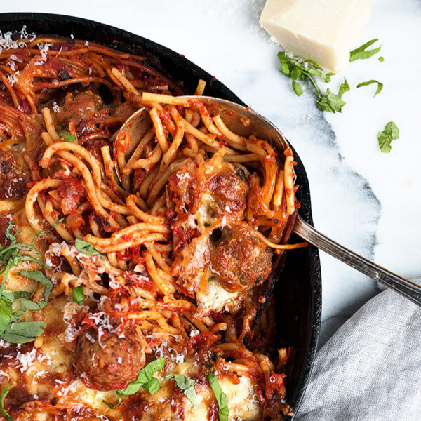 baked spaghetti and meatballs in cast iron skillet with spoon