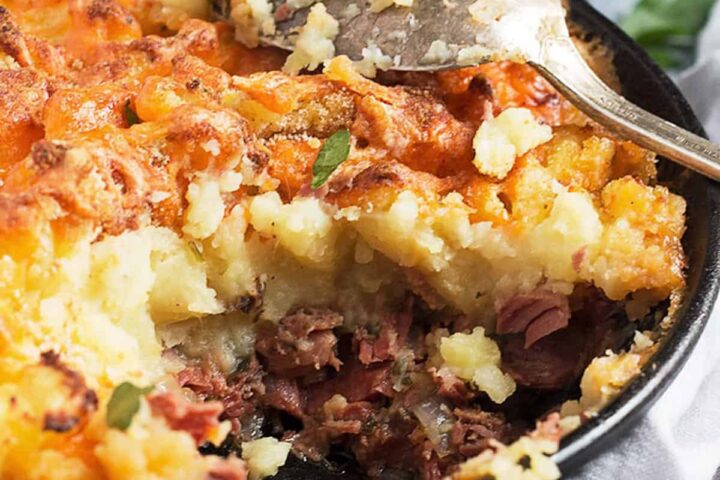 corned beef cottage pie in cast iron skillet with spoon