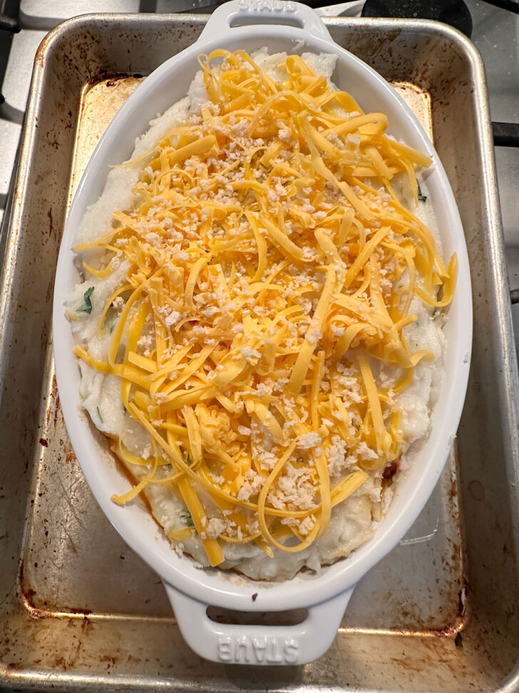 Potatoes topped with shredded cheese and breadcrumbs.