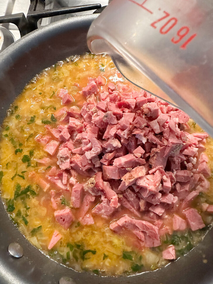 Adding corned beef to skillet.