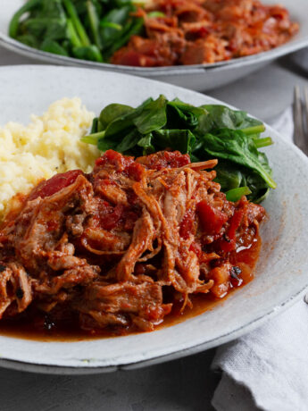 pork arrabbiata on plate with mashed potatoes and spinach