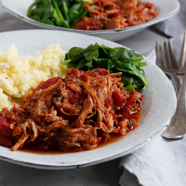 pork arrabbiata on plate with mashed potatoes and spinach