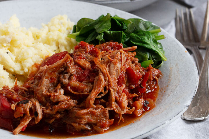 pork arrabbiata on plate with mashed potatoes and spinach